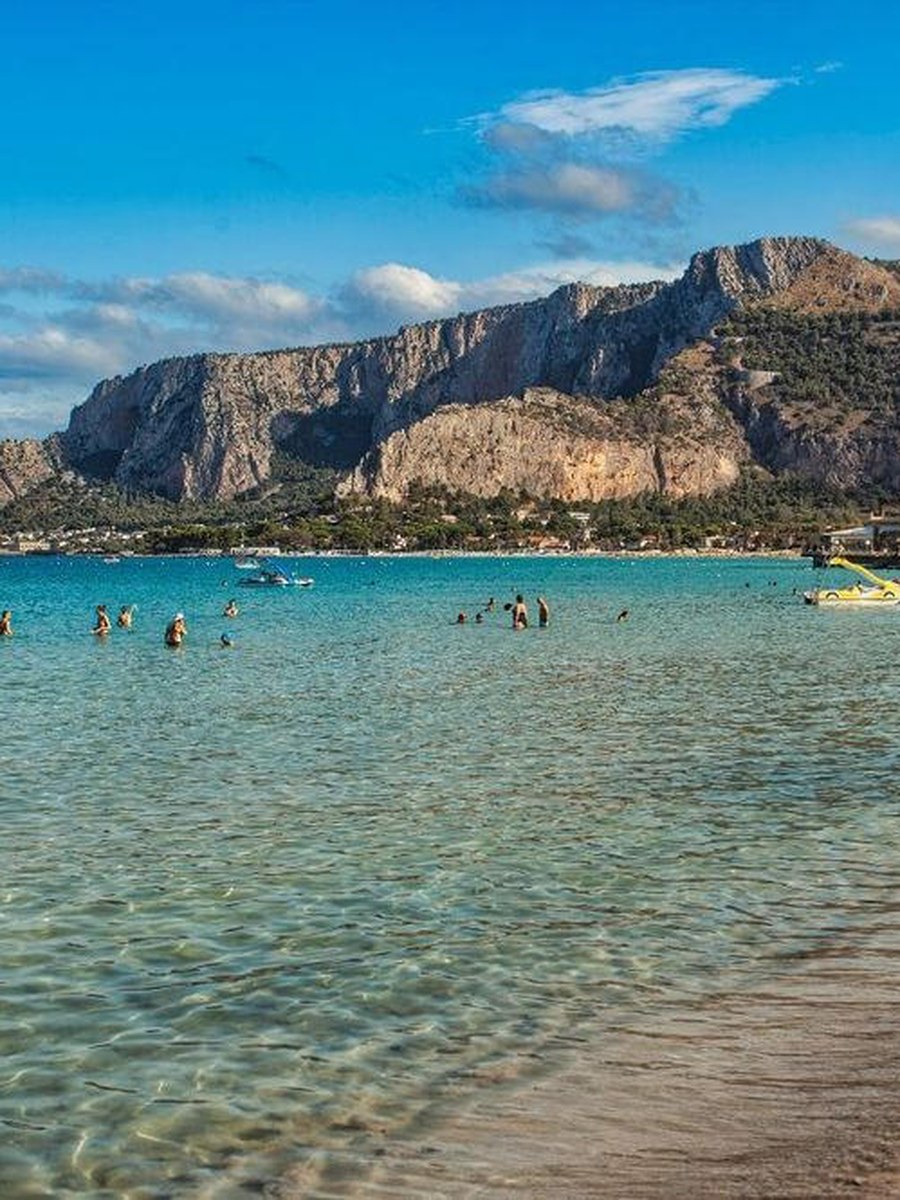 Pláž Mondello pri Palerme, ľudia v tyrkysovom mori pod skalou Monte Pellegrino